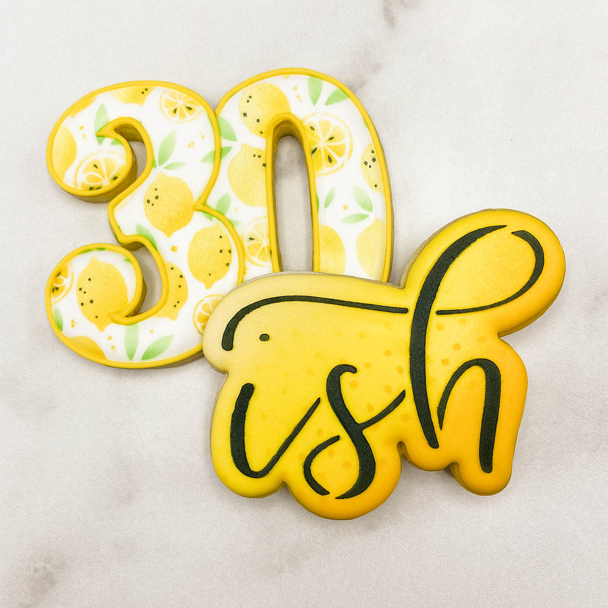 2 decorated cookies. #30 with lemon stenciled pattern and one that reads &quot;ish&quot;